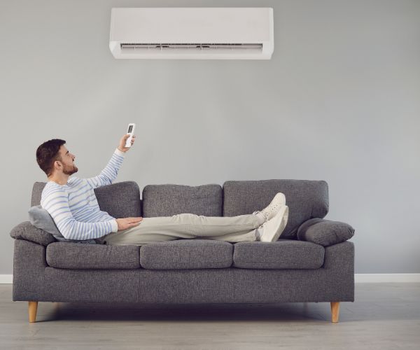 Man relaxing on a sofa under a cool, quiet split air conditioner